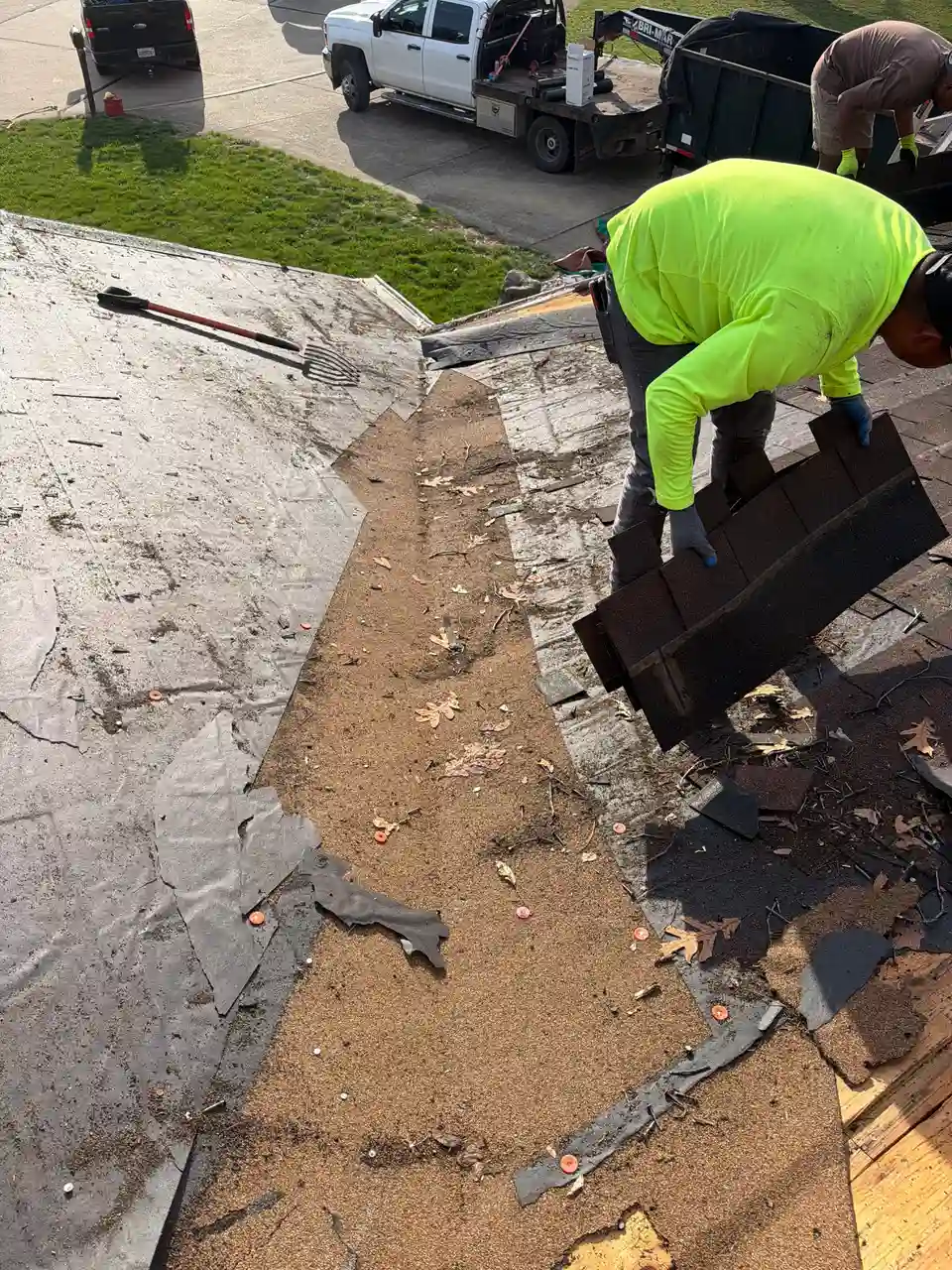 Roofer removing old shingles and underlayment to repair a roof leak on a Missouri home